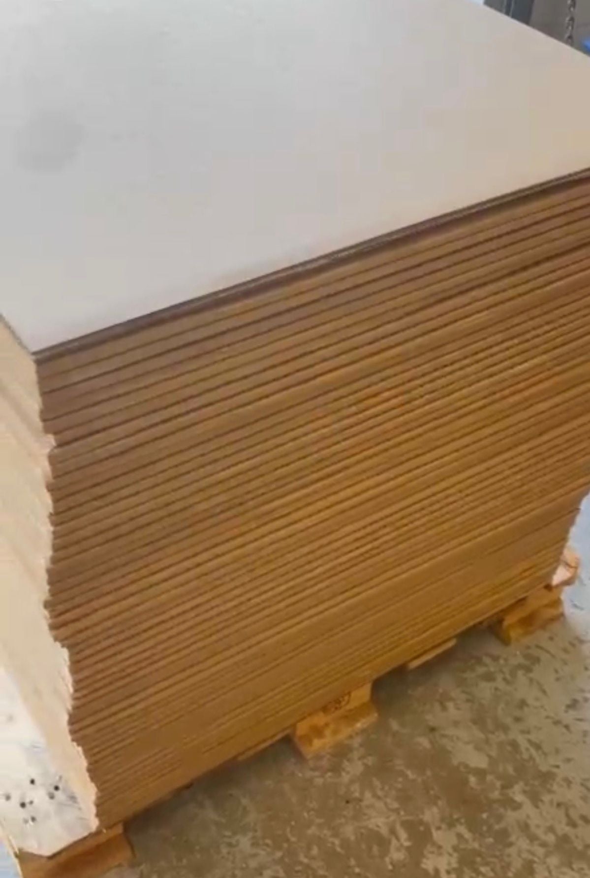 Stack of cardboard boxes on a pallet with a white surface above